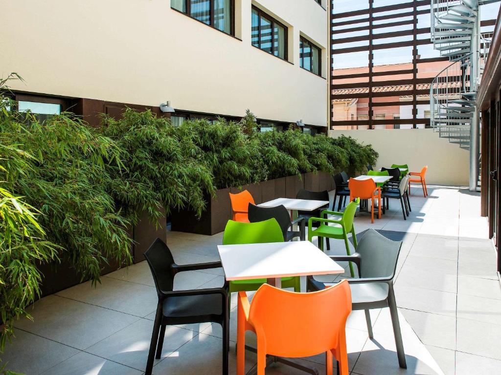 un patio al aire libre con mesas, sillas y plantas en Ibis Styles Collioure Port Vendres en Port-Vendres