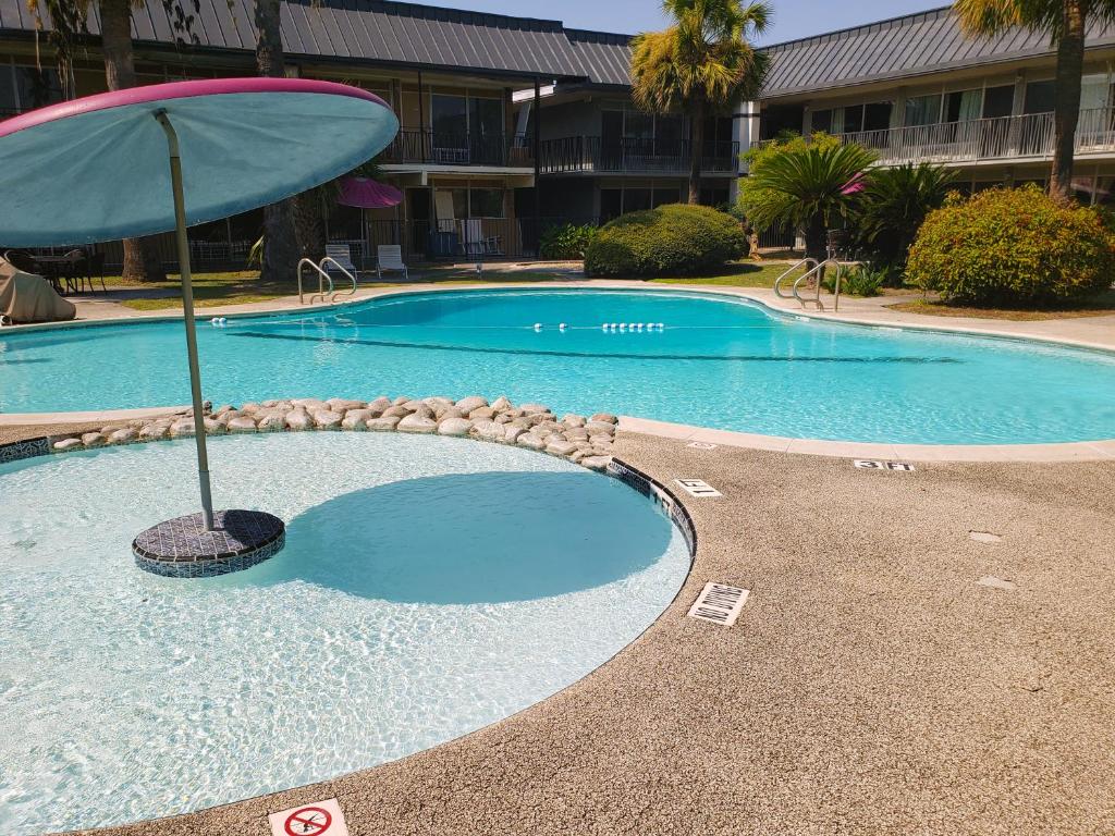 a swimming pool with an umbrella next to a building at Extended Stay SA in San Antonio