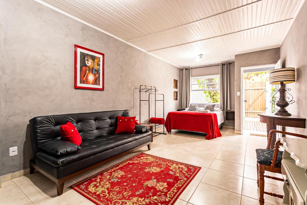 sala de estar con sofá negro y alfombra roja en Vintage Apartments Florianópolis, en Florianópolis