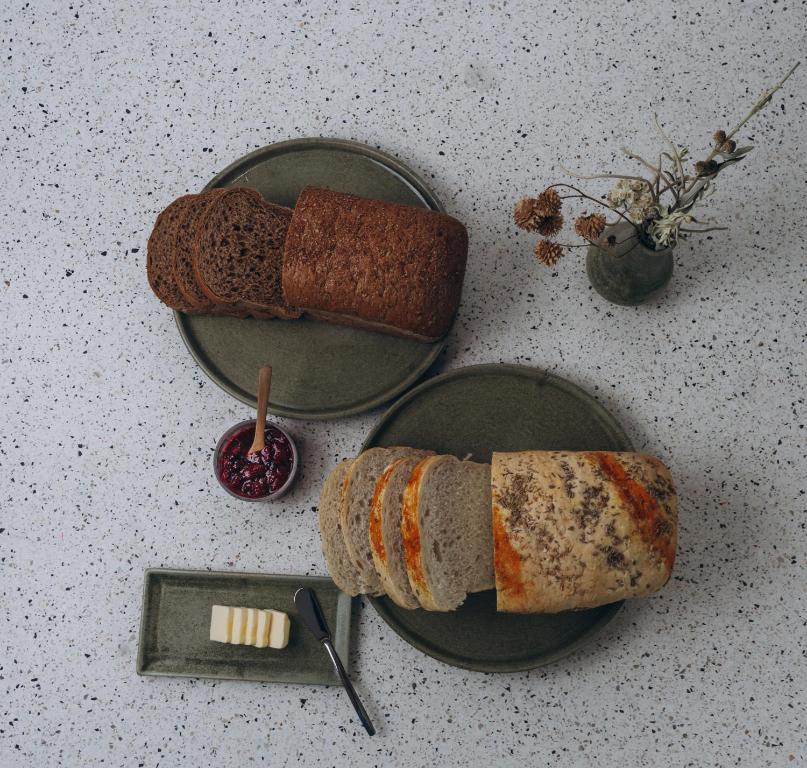 An overhead spread of sliced breads with butter, jam, and dried flowers.