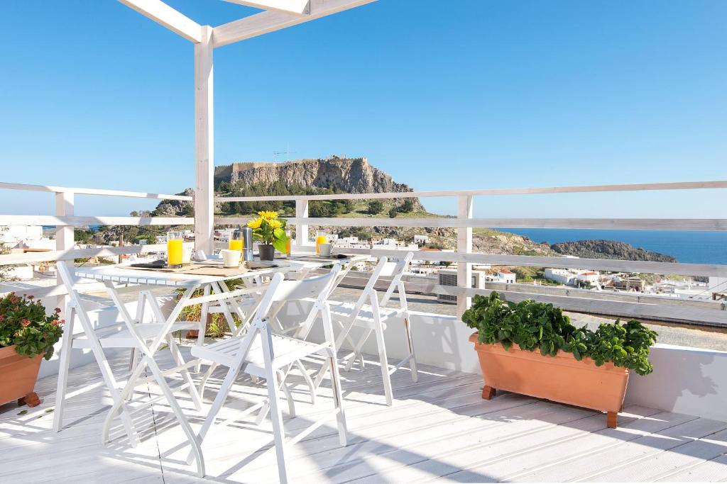 a balcony with tables and chairs and the view of the ocean at Lindos Harmony Suites in Líndos