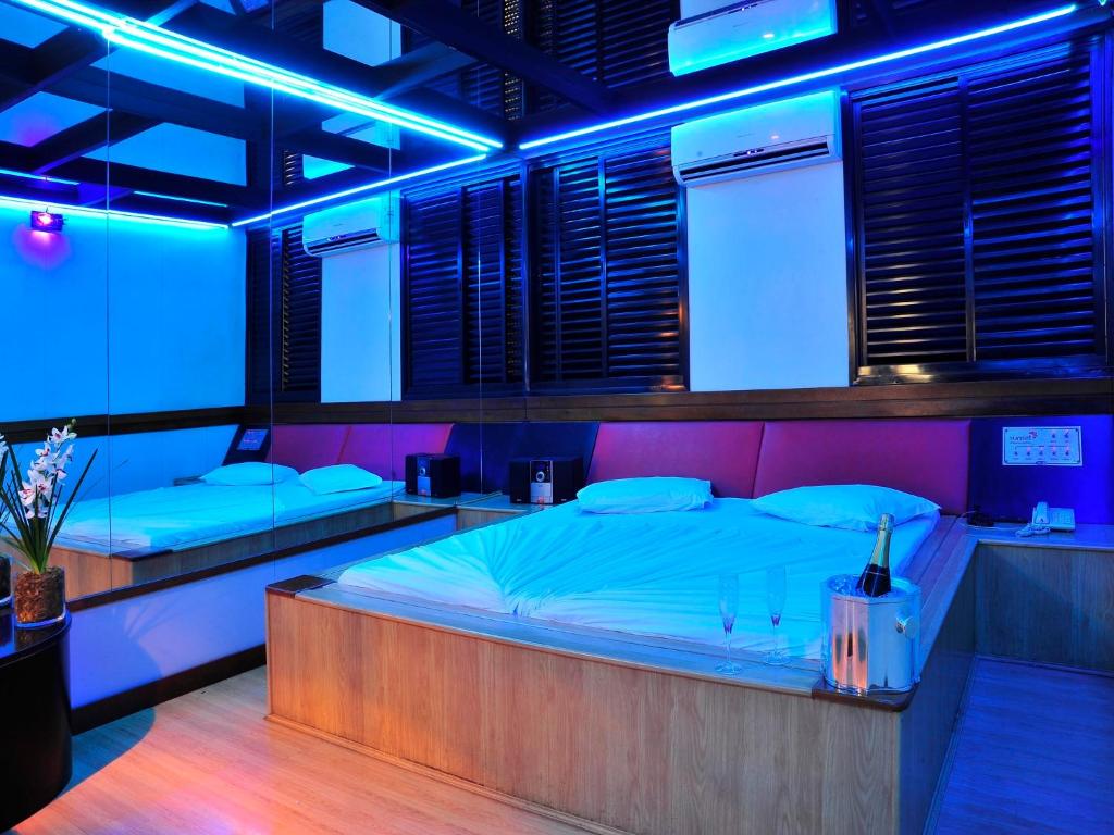 a room with two beds with blue lights at Motel Sunset (Adult Only) in Belo Horizonte