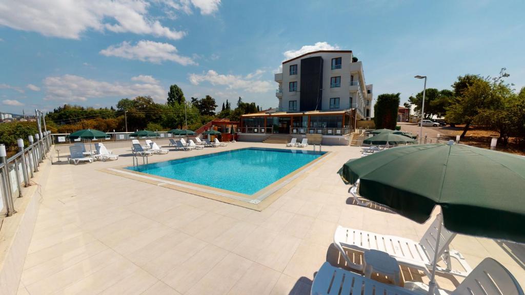 a pool with chairs and umbrellas next to a building at DOUBLE ROYAL HOTEL in Kocaeli