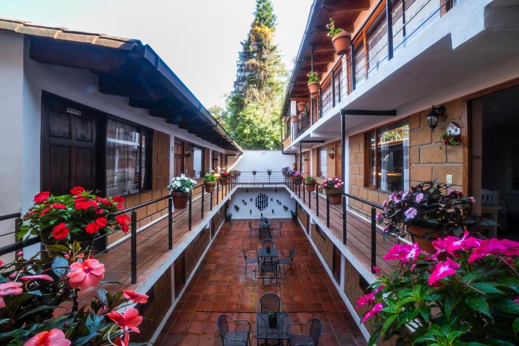un balcón de un edificio con flores, mesas y sillas en Hotel Rincon Soñado, Valle de Bravo en Valle de Bravo