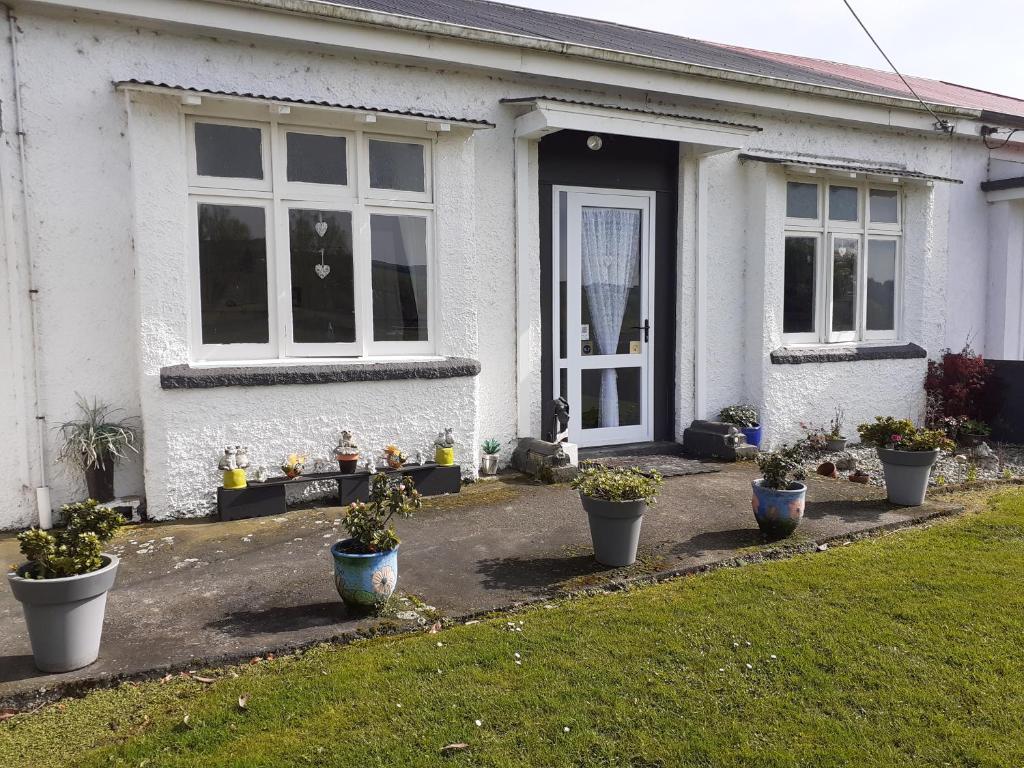 a white house with potted plants in front of it at Ellie's Villa in Brydone