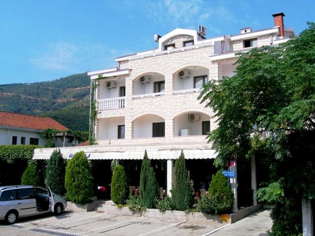 un grand bâtiment blanc avec des voitures garées devant lui dans l'établissement Hotel Grbalj, à Budva