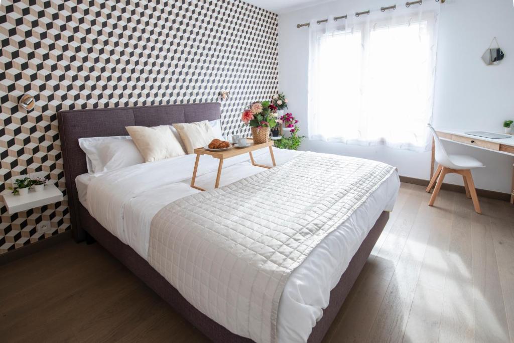 Un dormitorio con una cama grande y una mesa. en La Villa et sa plume, en Divonne-les-Bains