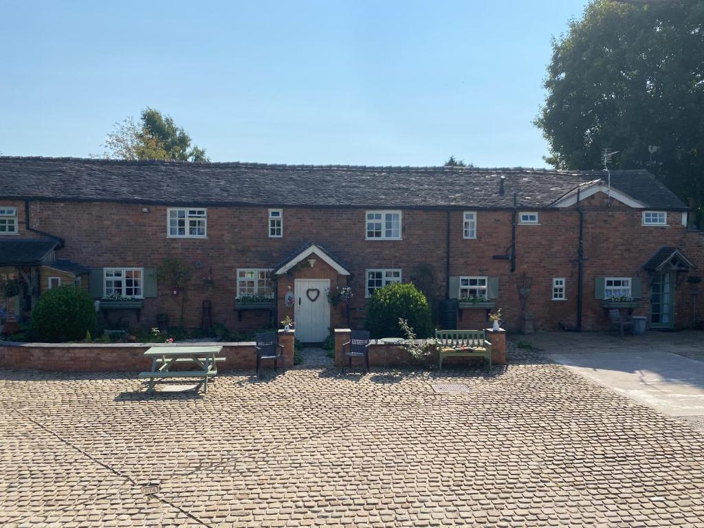 a large brick building with a courtyard with benches at Bank Farm Cottages in Nantwich