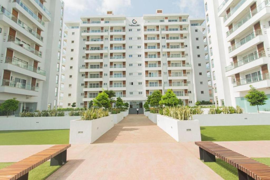 un grand bâtiment blanc avec des bancs devant lui dans l'établissement The Gallery Luxury Apartments, à Accra