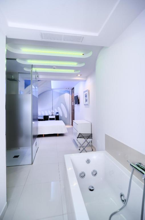 a white bathroom with a tub and a bed at Hotel Boutique Sabbia Valencia in Valencia