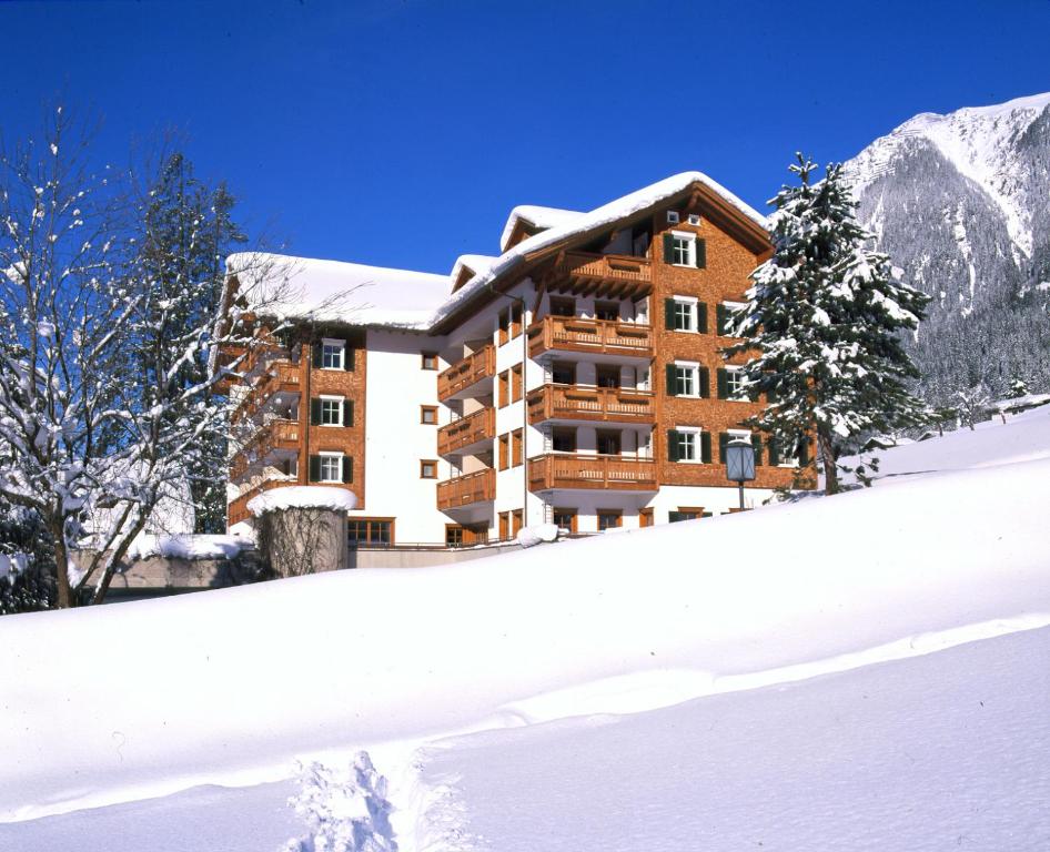 un bâtiment dans la neige devant une montagne dans l'établissement Posthotel Rössle, à Gaschurn