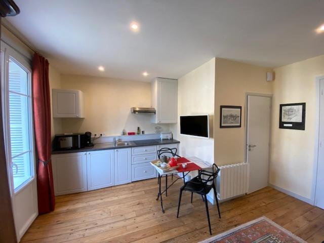 uma cozinha com armários brancos e uma mesa e cadeiras em Kereden Location em Saint Malo