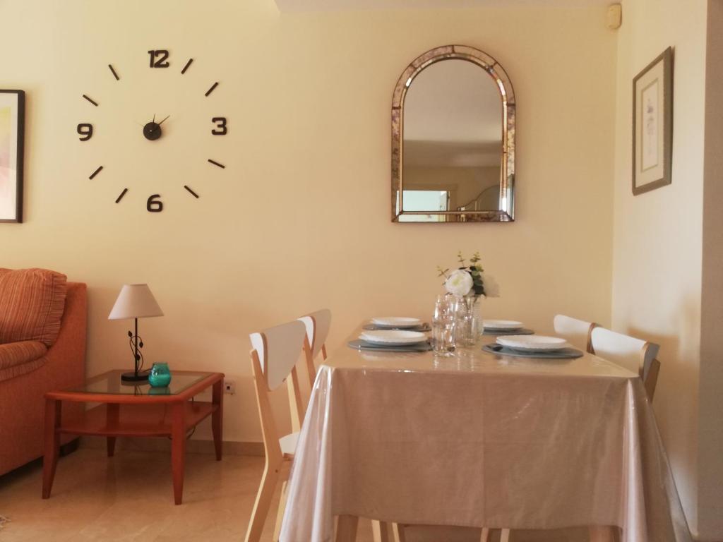 una sala da pranzo con tavolo e orologio sul muro di Bonito y tranquilo apartamento , cerca del mar. a Torrox Costa
