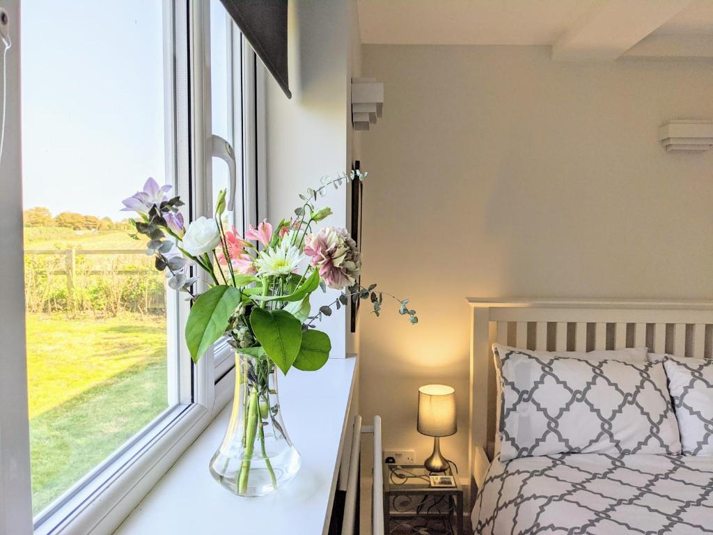 a vase of flowers sitting on a table next to a window at Cottars in Winfrith Newburgh