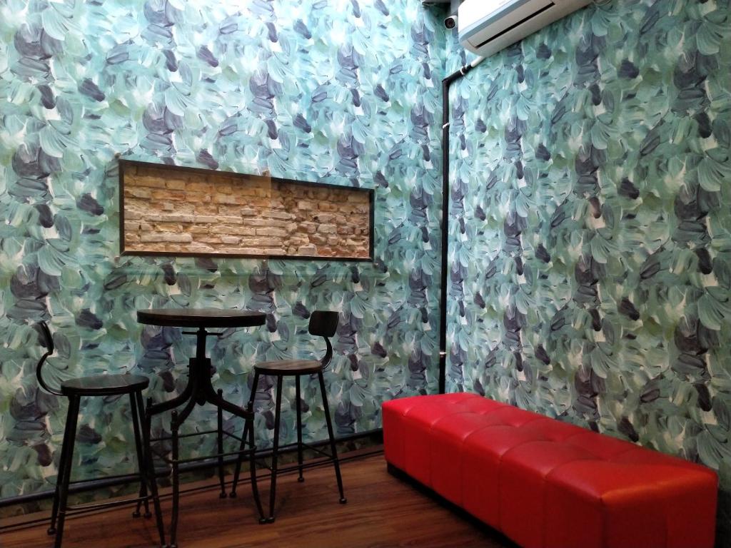 a room with a table and two stools and a wall at JOKA-JOKA GUESTHOUSE in Melaka