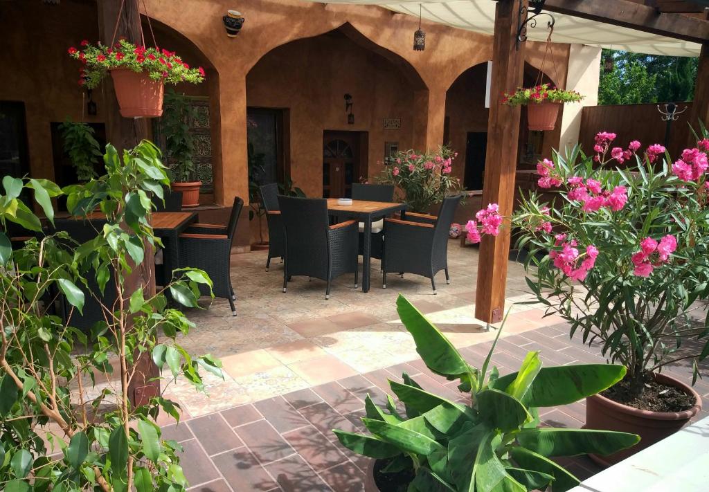 un patio al aire libre con mesas, sillas y flores en Hacienda Apartmanok en Eger