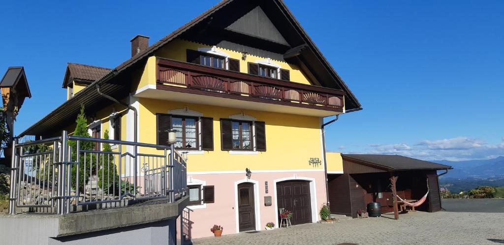 a yellow and pink house with a balcony at Wein- und Weitblick in Gleinstätten