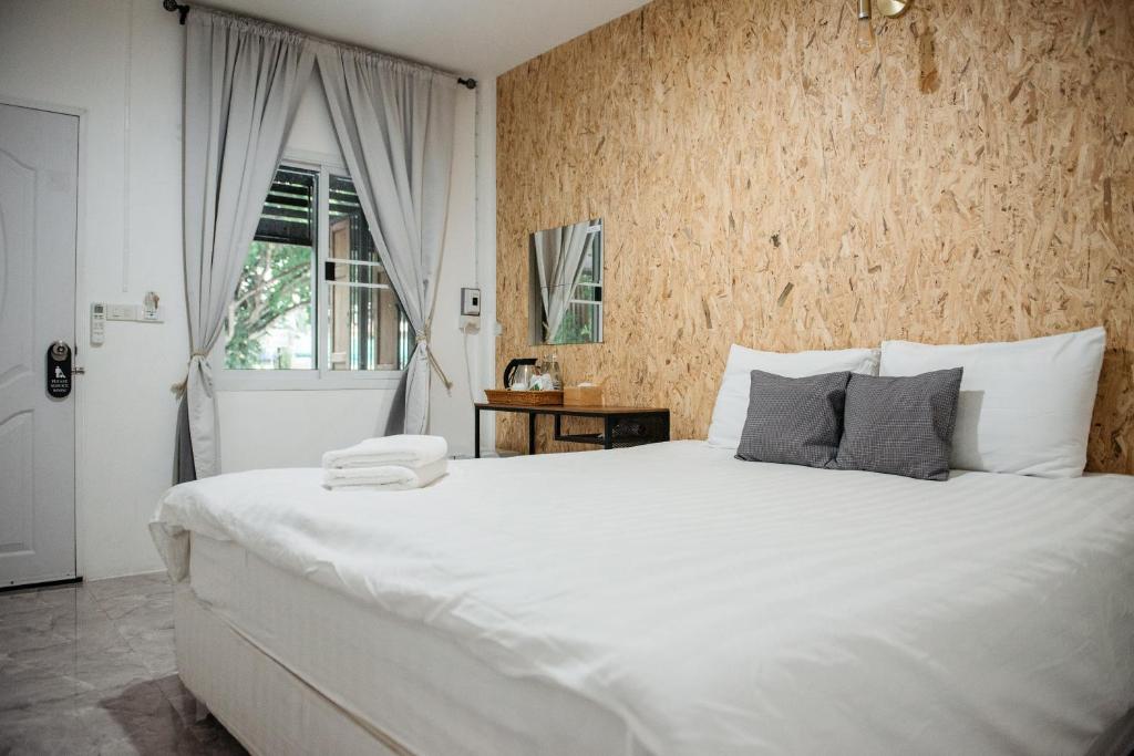 a bedroom with a large white bed and a window at Lamoon Boutique Hotel in Suphan Buri