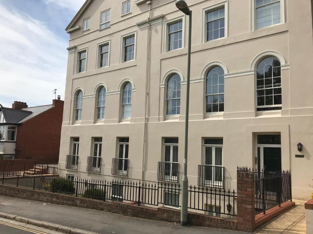 a white building with a fence in front of it at Luxury City Centre Apartment, Exeter. in Exeter