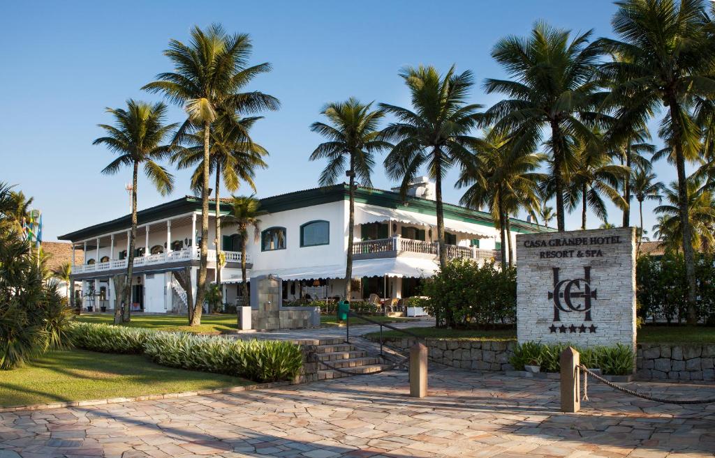 a large white building with palm trees in the background at Casa Grande Hotel Resort & Spa in Guarujá