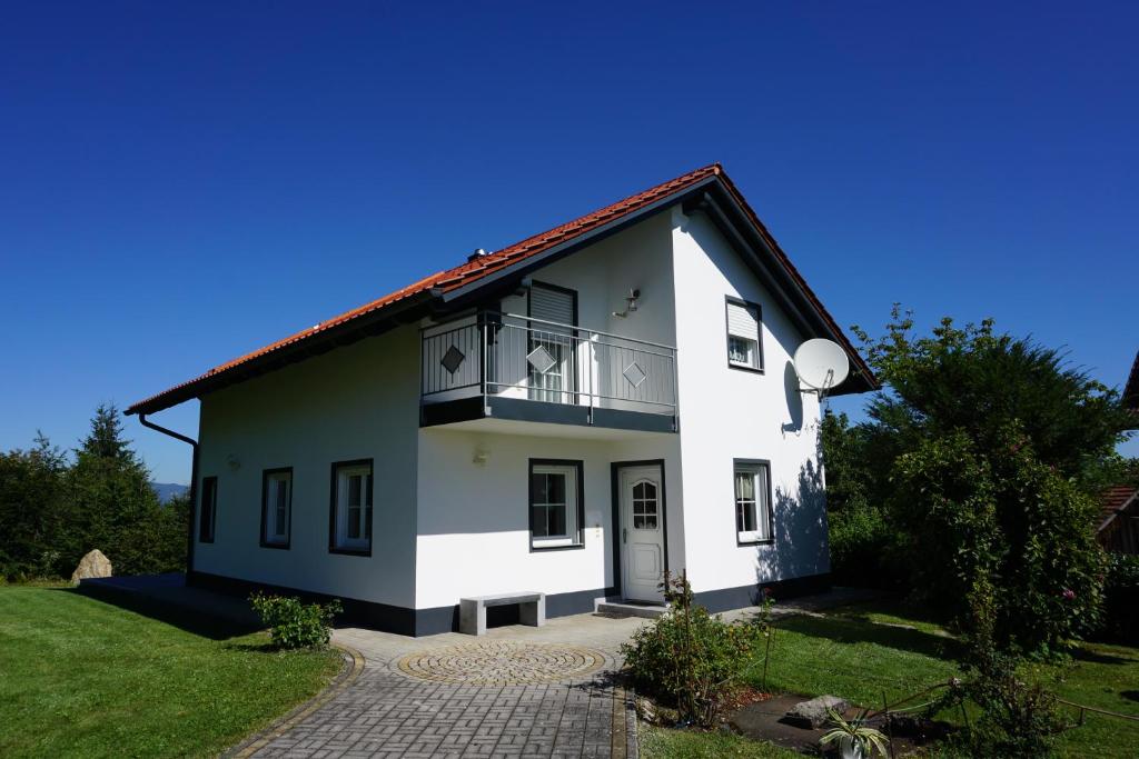 uma casa branca com uma varanda num quintal verde em Ferienhaus Englburg in absolut ruhiger Lage em Tittling