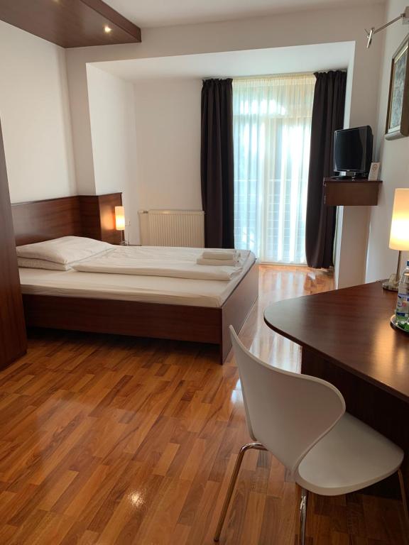 Hotel Arli في سينيتسا: غرفة نوم بسرير وطاولة وكرسي