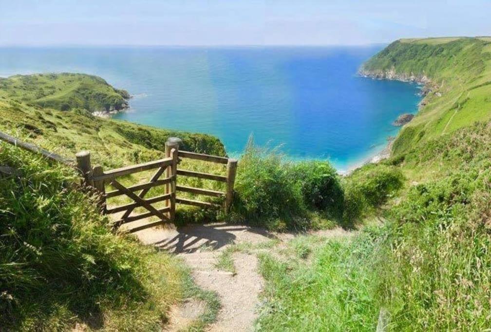 una valla de madera en una colina cerca del océano en Talehay Cottages en Looe