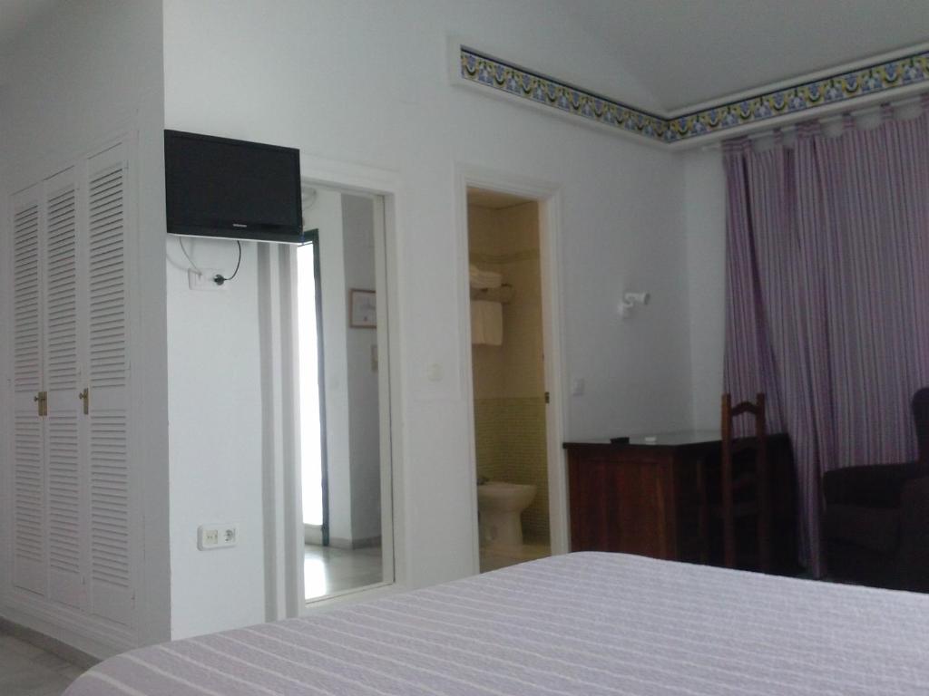 1 dormitorio con 1 cama y TV en la pared en Los Helechos, en Sanlúcar de Barrameda