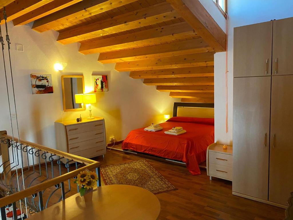 Schlafzimmer mit einem roten Bett und Holzdecken in der Unterkunft Azzurromare Apartment in Syrakus