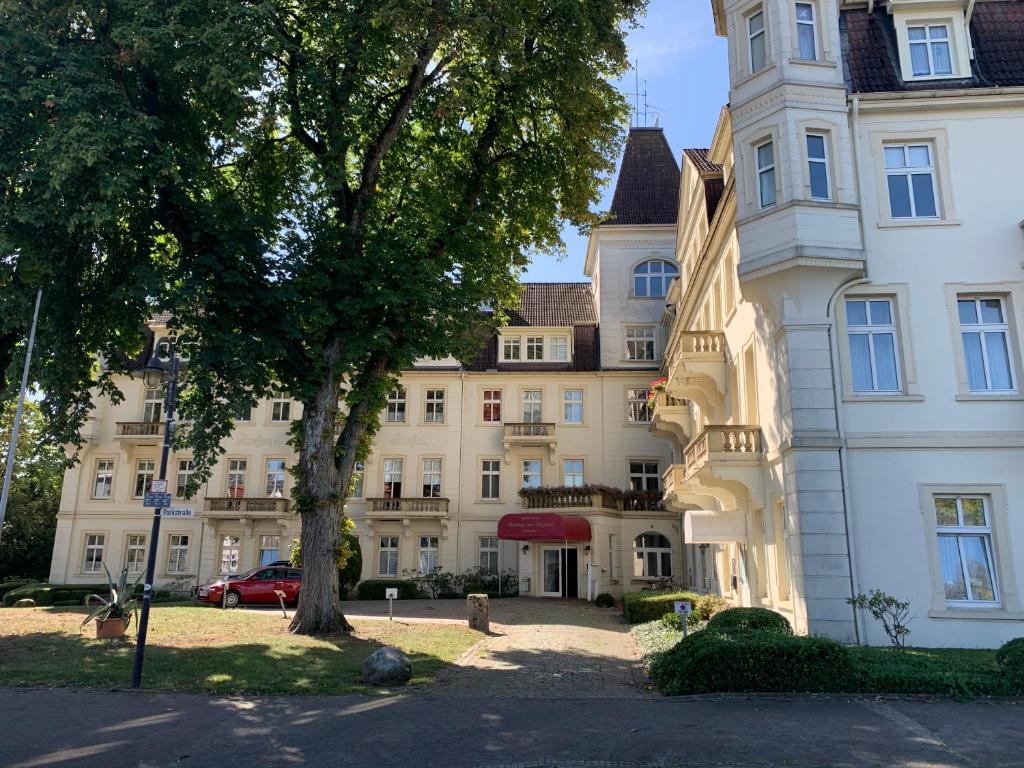 a large white building with a tree in front of it at Gala Apartment am Kurpark in Bad Rothenfelde