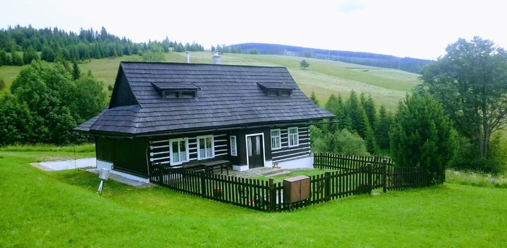 une petite maison avec un toit noir sur un champ verdoyant dans l'établissement Drevenica Goralský Dvor, à Ždiar