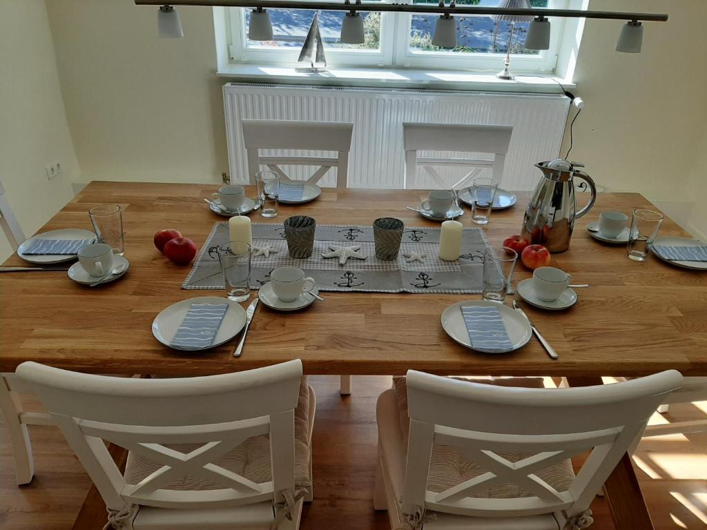 a wooden table with white chairs and a wooden table with plates and glasses at Ferienwohnung Hans & Elsa in Neudorf-Bornstein