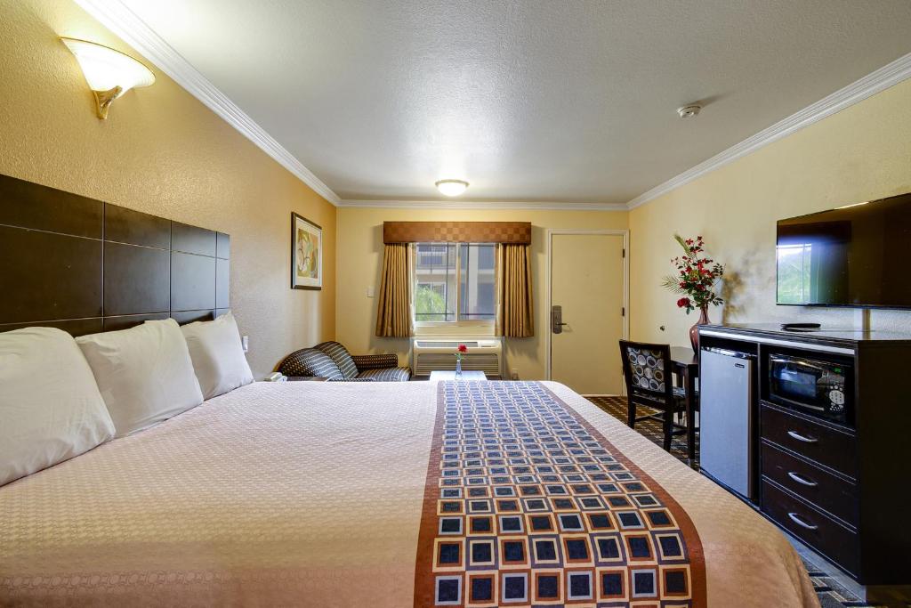 a hotel room with a large bed and a kitchen at Hacienda Inn in La Puente