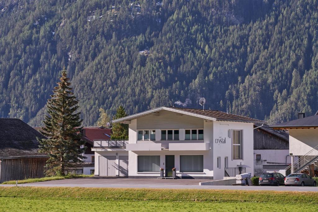 a white house with a mountain in the background at Apart Crystal in Längenfeld