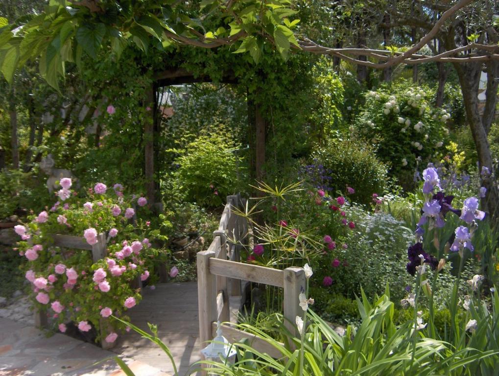 um jardim com um banco de madeira e flores em Lou Pero Mousco em Saint-Paul-en-Forêt