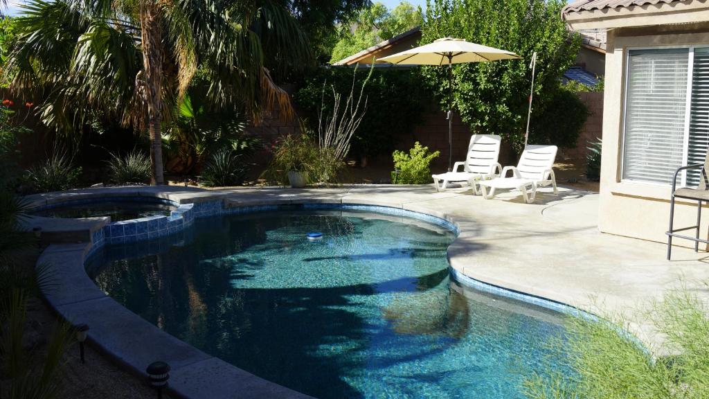 einen Pool im Hinterhof mit Sonnenschirm in der Unterkunft 3 bedroom house with Private Pool, Spa&Golf Course! in La Quinta