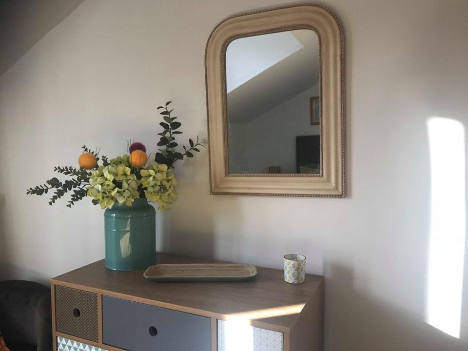 un tavolo con un vaso di fiori e uno specchio di Le Carpé Diem, Cosy, Confort, Cocooning, 90 m² a Saint-Léonard-de-Noblat