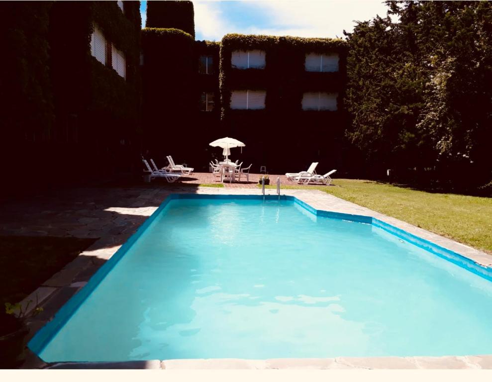 une grande piscine bleue avec une table et des chaises dans l'établissement salto grande, à Punta del Este