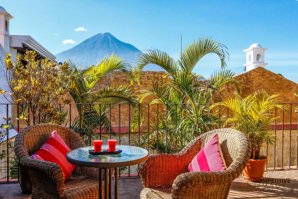 a patio with two chairs and a table and a mountain at Casa La Ermita in Antigua Guatemala