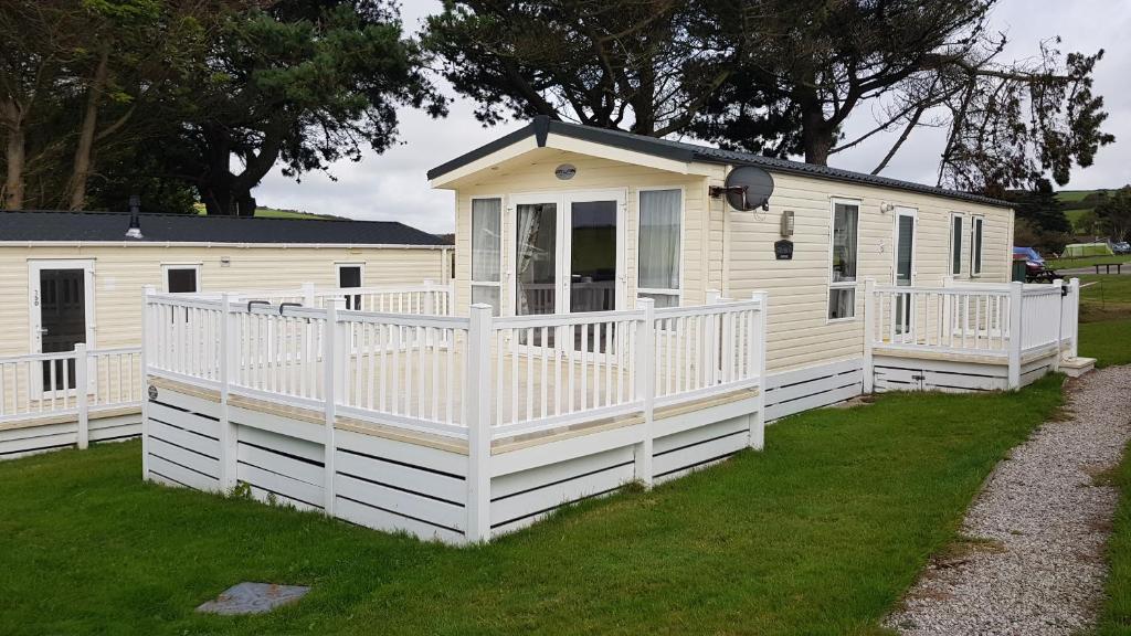 a white mobile home with a porch and a fence at Newquay Bay Resort 151 in Newquay