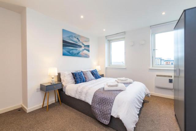 a bedroom with a large bed and two windows at Newcastle City Centre Apartment Ideal for Holiday, Contractors, Quarantining in Newcastle upon Tyne