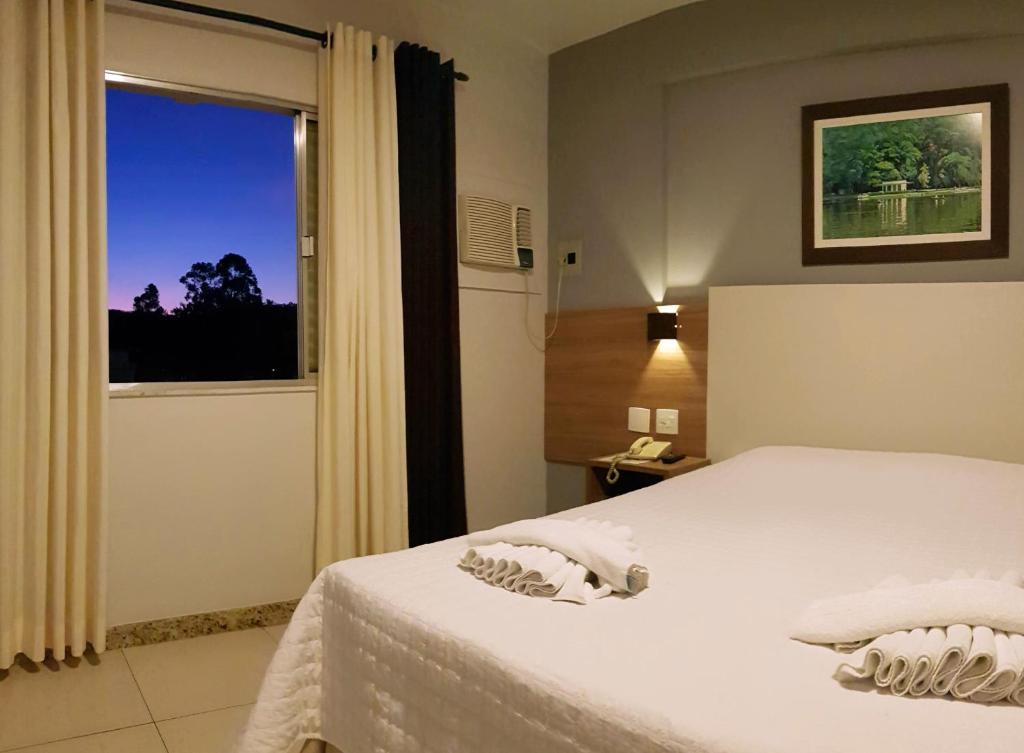1 dormitorio con cama blanca y ventana en Hotel Beira Parque, en São Lourenço