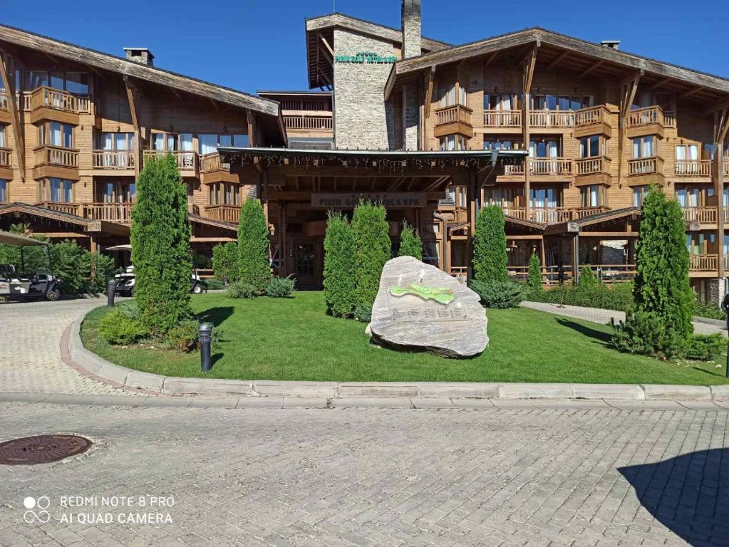 una roca en el césped delante de un edificio en Mountain view Private apartments in Pirin Golf and SPA resort, en Razlog