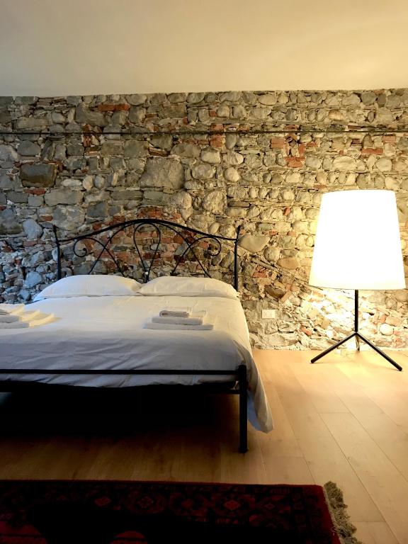 a bedroom with a stone wall with a bed and a lamp at Il Palazzetto - La terrazza di Elia in Cividale del Friuli