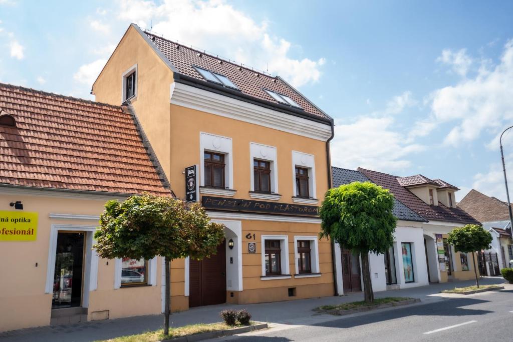 a yellow building with a brown roof at Penzión pod kláštorom in Pezinok