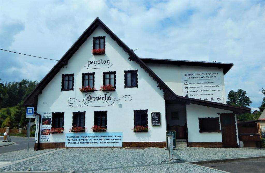 Penzion Dřevěnka في Osečná: مبنى أبيض وبه زهور على النوافذ