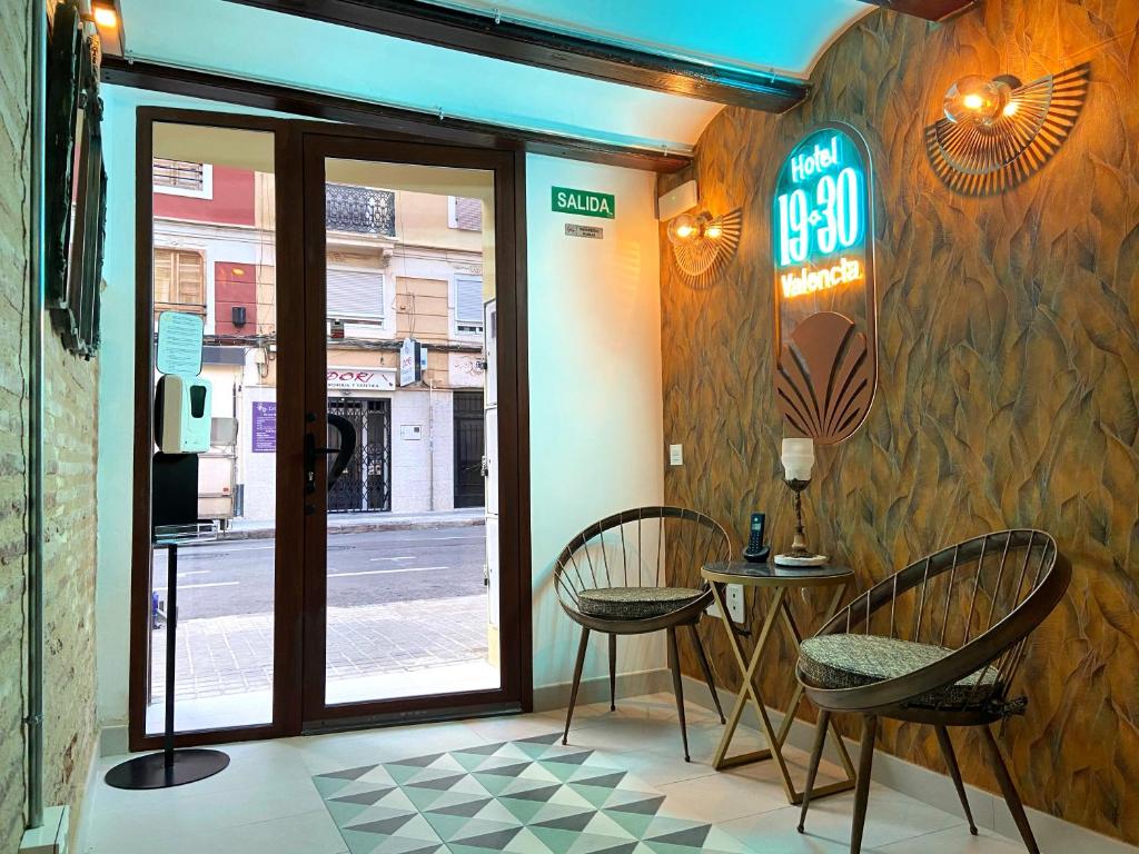 ein Restaurant mit zwei Stühlen und einem Tisch vor einer Tür in der Unterkunft Hotel 19-30 Valencia in Valencia
