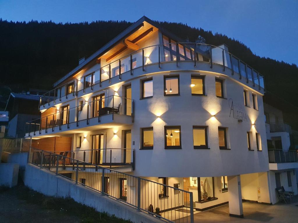 um grande edifício branco com luzes acesas à noite em Chasa Allegria em Ischgl