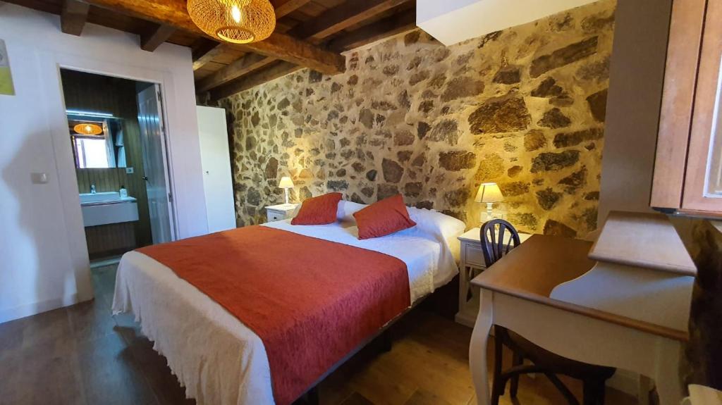 ein Schlafzimmer mit einem Bett in einem Zimmer mit Steinwänden in der Unterkunft Casas del Castillo, 1 in Avila