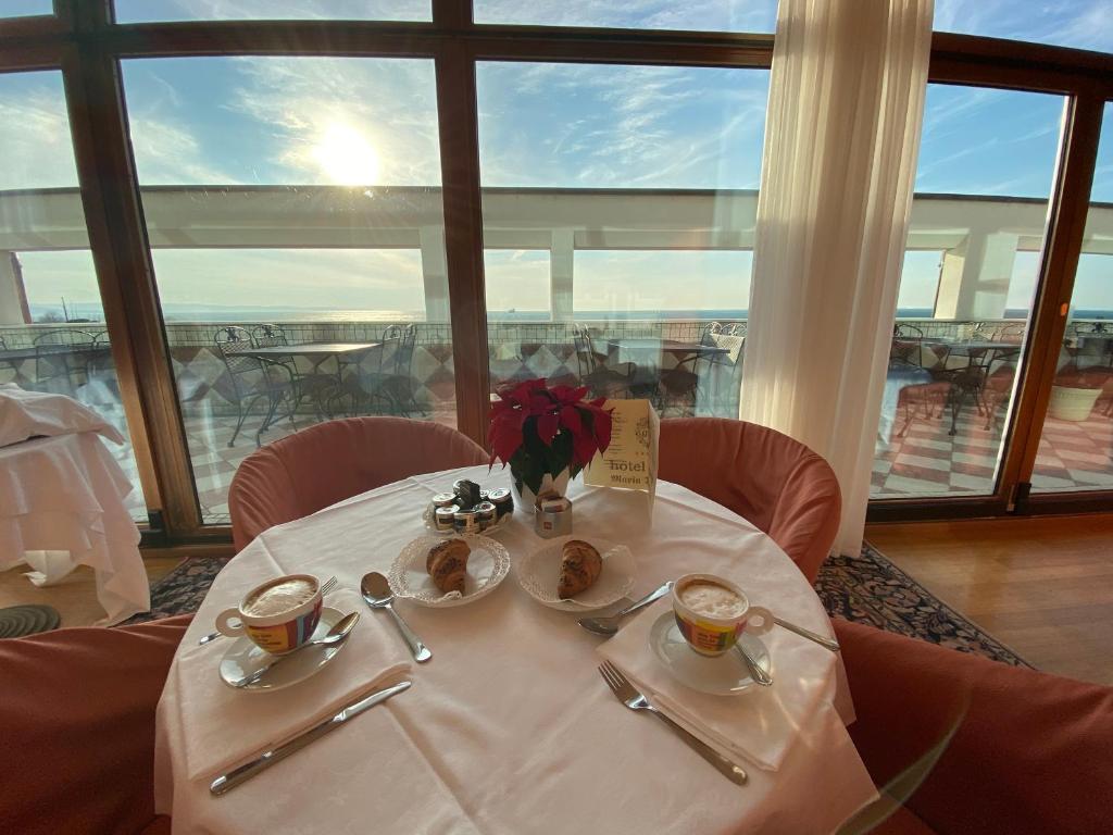 a table with two cups of coffee and food on it at Greif Hotel Maria Theresia in Trieste